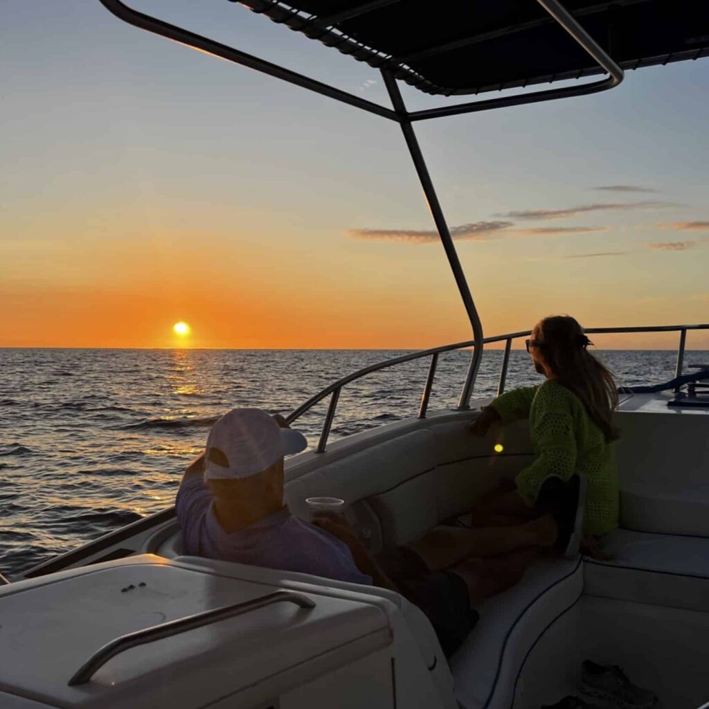 Passengers sitting in the boat with a sunset on the horizon